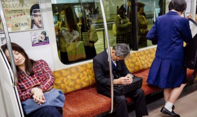 A man in a suit sleeps in a train in Japan