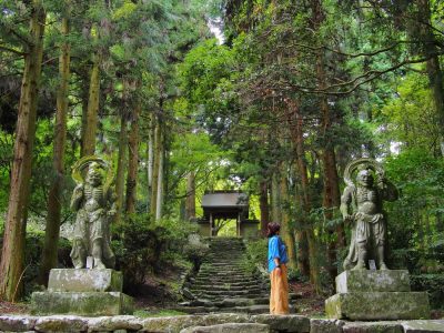 A woman standing in front of a temple in a Japanese forest
