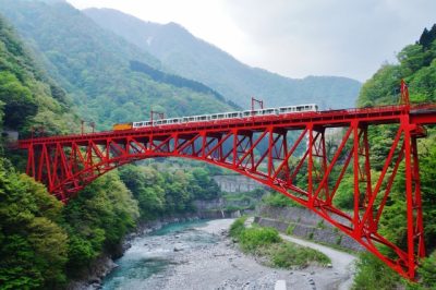 Train on a red bridge over the Kurobe Gorge in Toyama, Japan