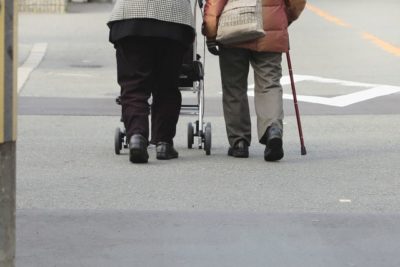 Two senior citizens walking with a rack and a stick in Japan