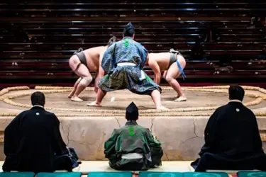 Two sumo wrestlers and a referee during a match in Japan